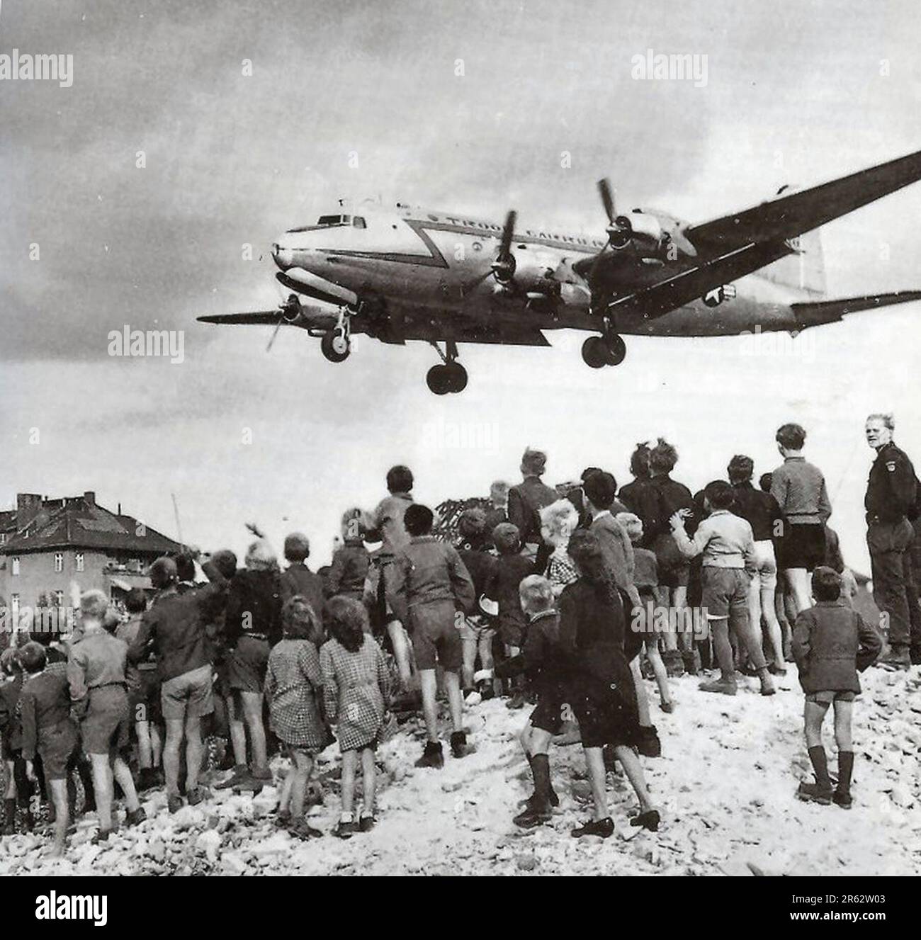 Berliner beobachten eine C-54-Landung am Flughafen Berlin-Tempelhof während des Berliner Luftwegs 1948. Als Reaktion auf die eskalierenden Spannungen und auf die Einführung einer neuen westdeutschen Währung unterbrachen die Sowjets alle Landverbindungen nach Westberlin und beendeten den Transport von Nahrungsmitteln dorthin. Die Antwort von Allied war eine elfmonatige Kampagne, um W Berlin mit den 5000 Tonnen Nahrung und Treibstoff pro Tag zu versorgen, die es benötigte. Ein Flugzeug landete Tag und Nacht alle drei Minuten und die Operation war so erfolgreich, dass die Sowjets zurückweichen und die Straßen, Eisenbahnen und Kanäle wieder öffnen mussten. Stockfoto