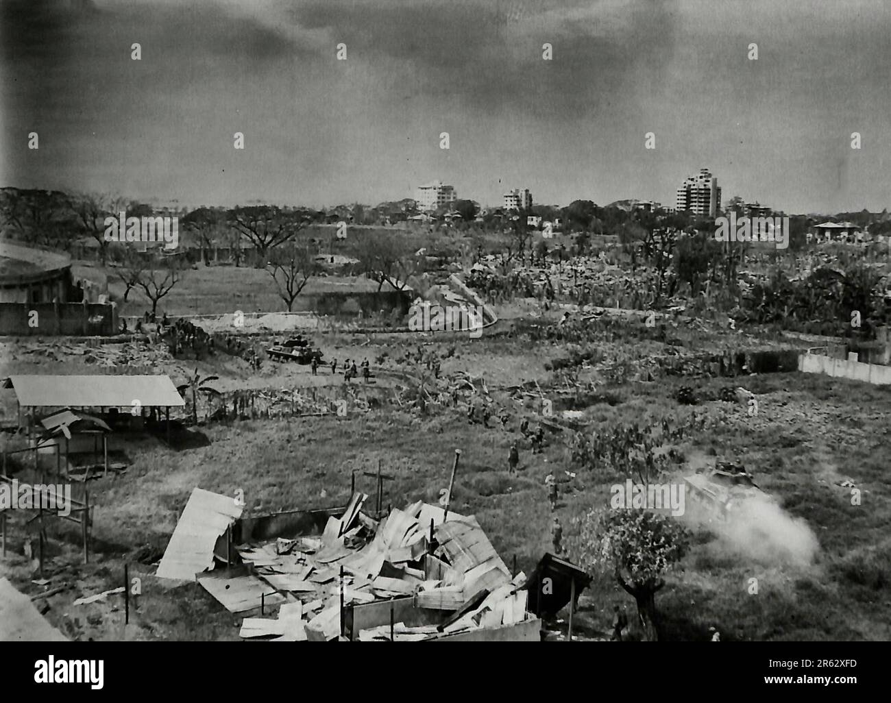 Blick vom Dach des La Salle Girls College in Manila, mit Blick auf das Rizal Stadium im Hintergrund. Hier sind Panzer, die auf dem Fußballfeld einmarschieren, mit Truppen dahinter. Der Graben in der Mitte des Bildes stellte eine gewaltige Panzerbarriere dar, bis ein amerikanischer Bulldozer auftauchte und ihn mit Erde füllte. Februar 1945 Stockfoto