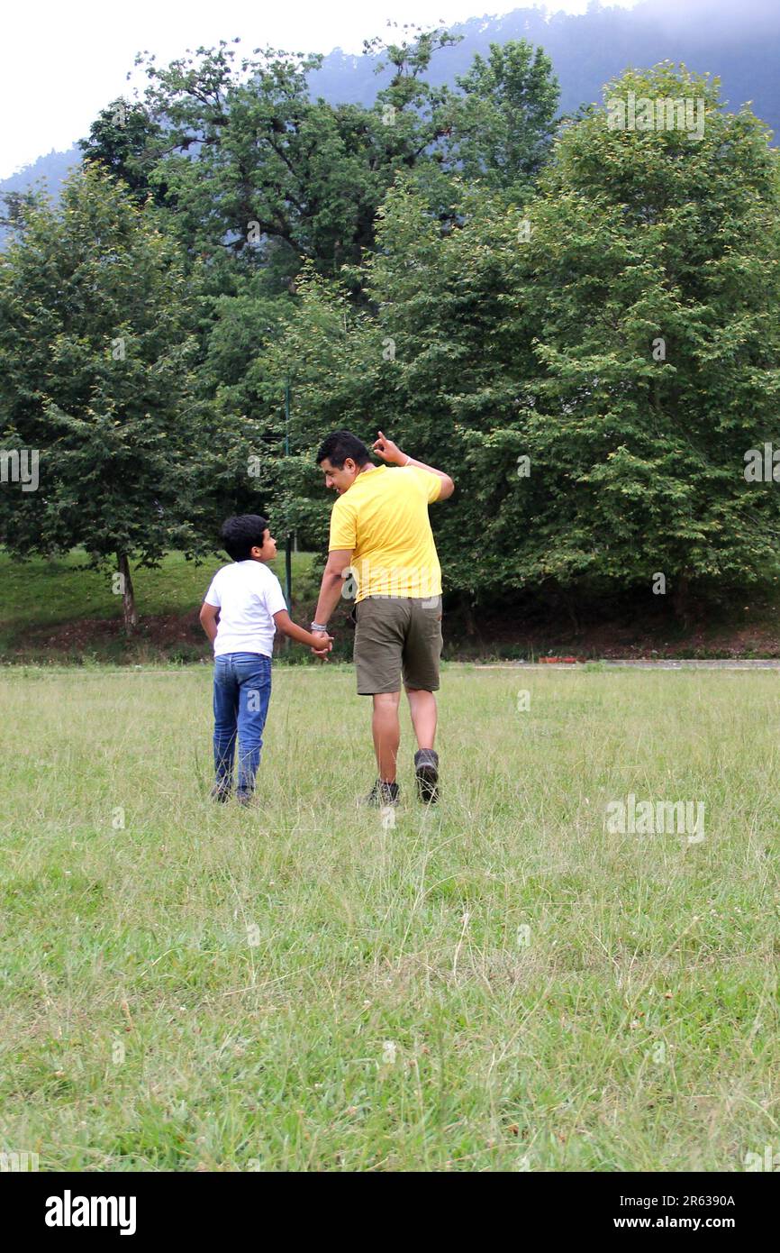 Geschiedener alleinerziehender Vater und 9-jähriger Sohn, braunhaariger Latino, wandern durch die Landschaft und schauen Hand in Hand in Hand in die Zukunft Stockfoto