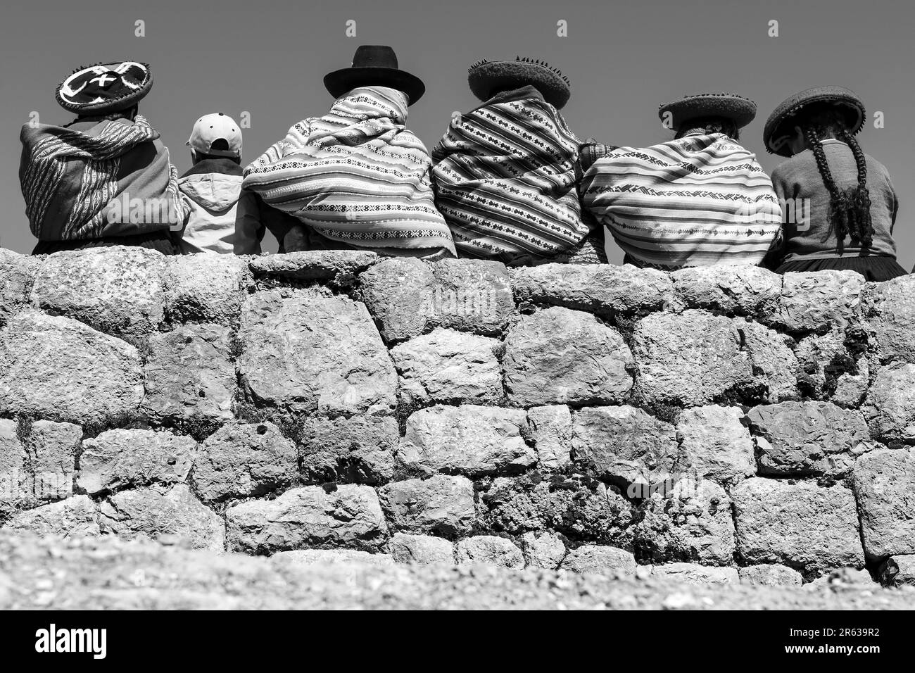 Peruanische Ureinwohner von Quechua auf der Inka-Mauer in Schwarz und Weiß, Chinchero, Cusco, Peru. Stockfoto