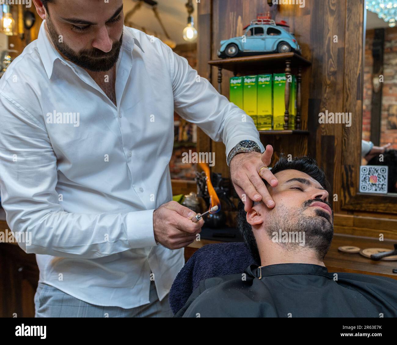 Ein professioneller Friseur, der das Haar eines Kunden mit einer kleinen Taschenlampe stylen kann, um einen einzigartigen Look zu schaffen Stockfoto