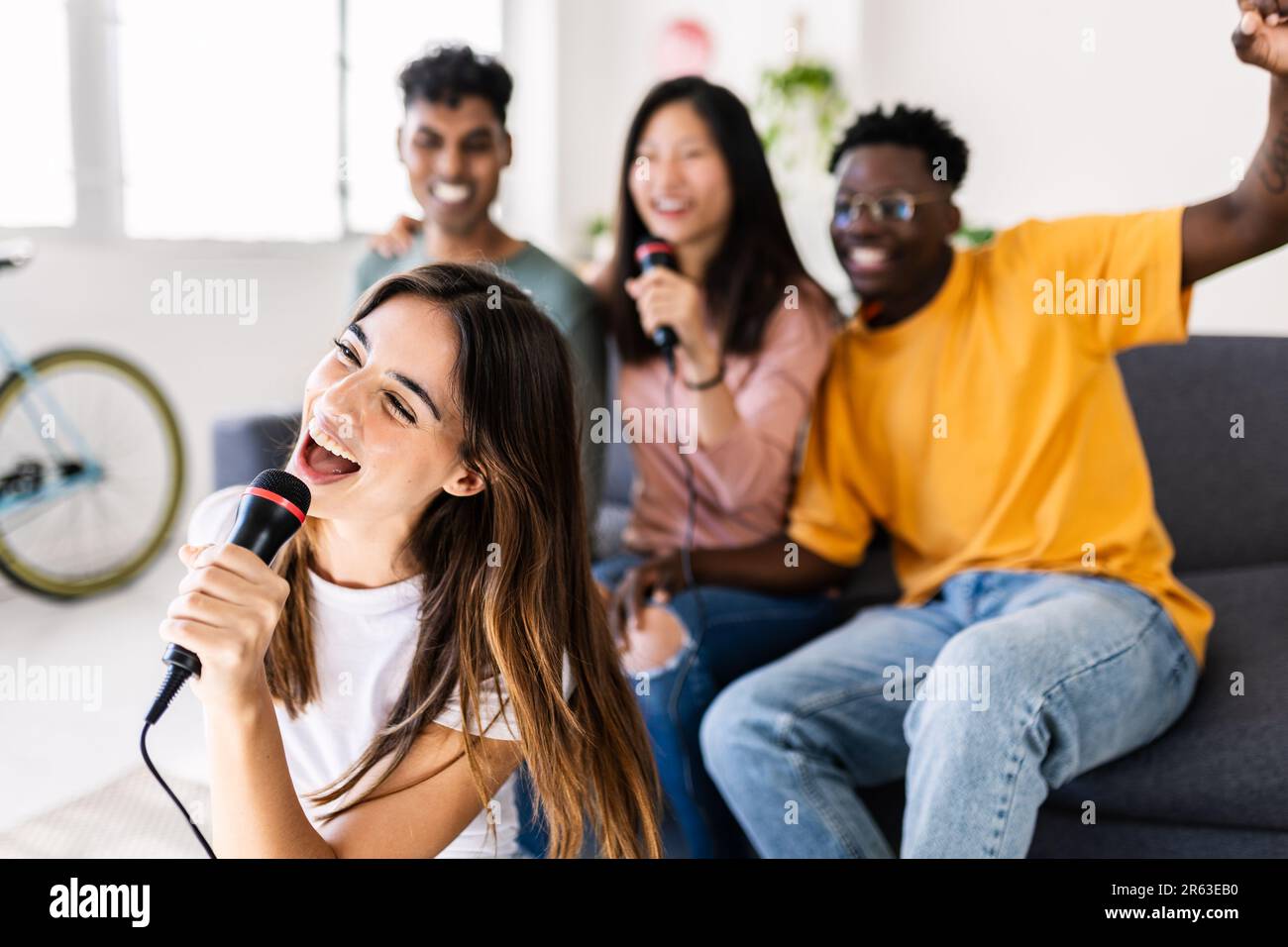 Eine Gruppe von Freunden, die Spaß beim Karaoke-Spielen auf der Heimparty haben Stockfoto