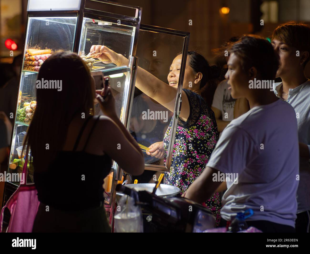 Eine Frau, die nachts Hot Dogs und Fleischbällchen auf der Straße verkauft, in Ho Chi Minh City, Distrikt 1, Vietnam. Stockfoto