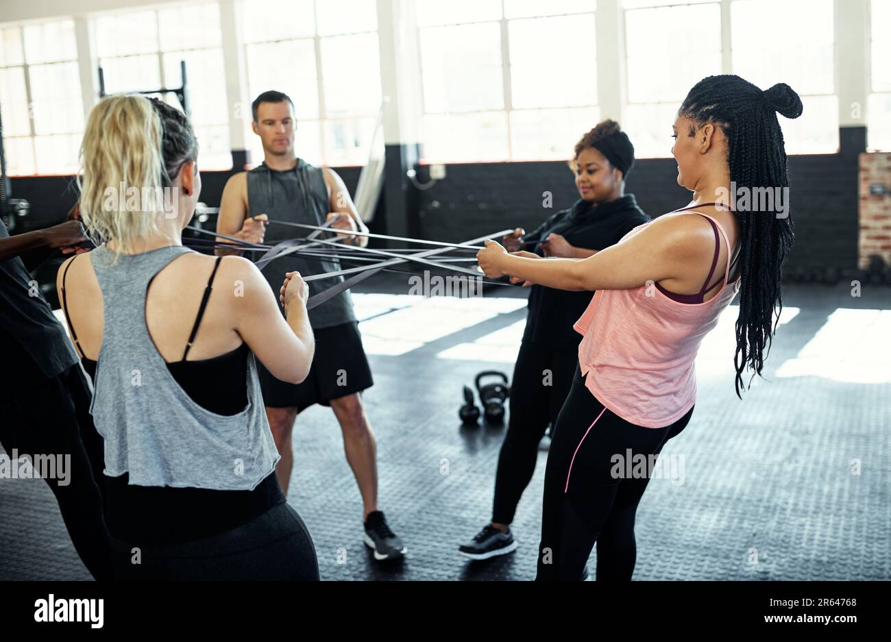 Zusammen können Sie so viel mehr erreichen. Eine Fitnessgruppe, die im Fitnessstudio mit Widerstandsbändern trainiert. Stockfoto