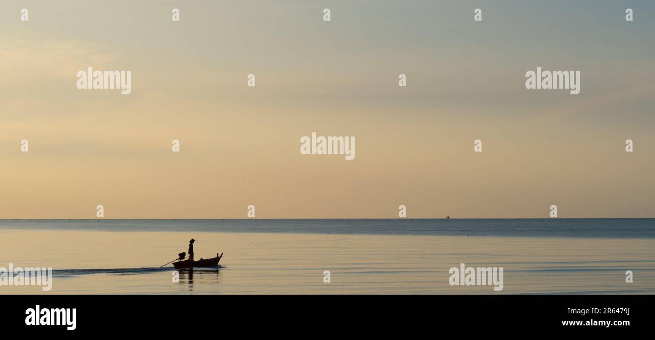Silhouettenfischer, die am frühen Morgen auf das offene Meer segeln. Sehr friedliche Atmosphäre und ruhiges Meer ohne Wellen. Stockfoto