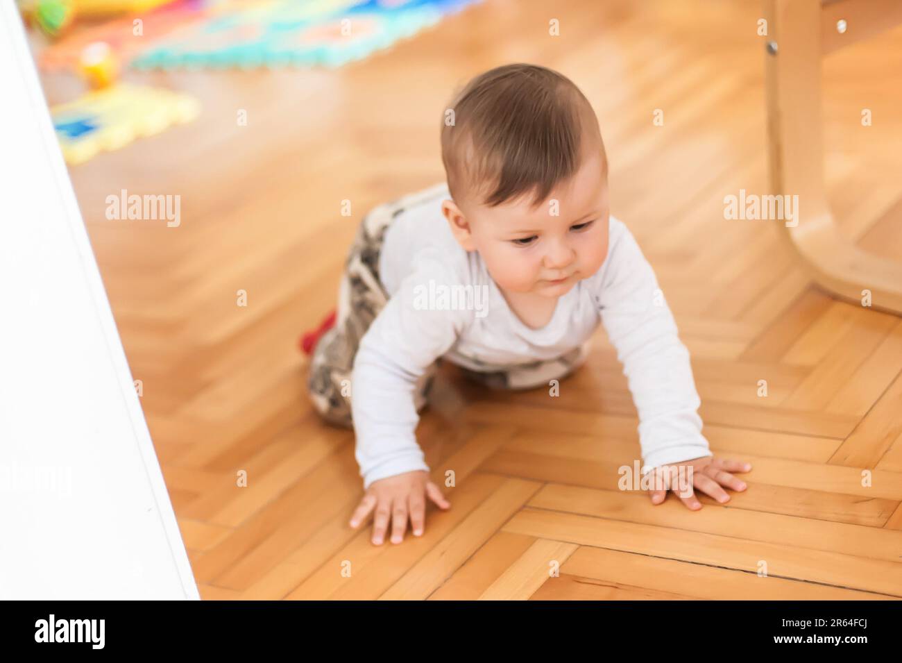 Der süße Junge krabbelt auf dem Hausboden herum, erkundet die Welt und lernt, sich zu bewegen. Vorderansicht. Liebe und Familiengefühle Stockfoto