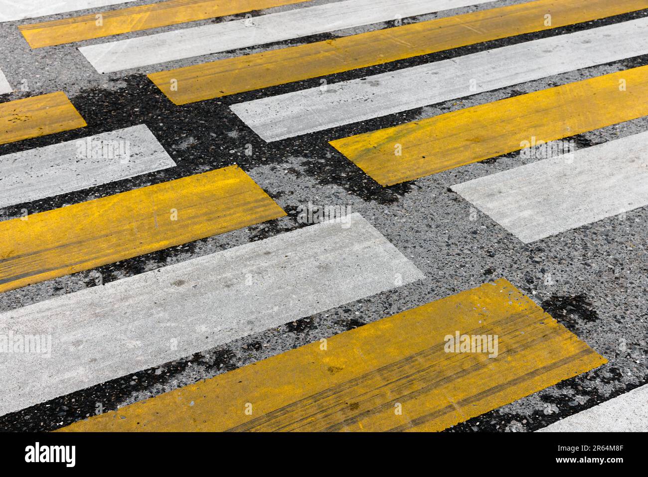 Gelbe weiße Streifen über Asphaltpflaster. Fußgängerüberquerung, Straßenmarkierung Zebra, Hintergrundfoto für städtischen Transport Stockfoto