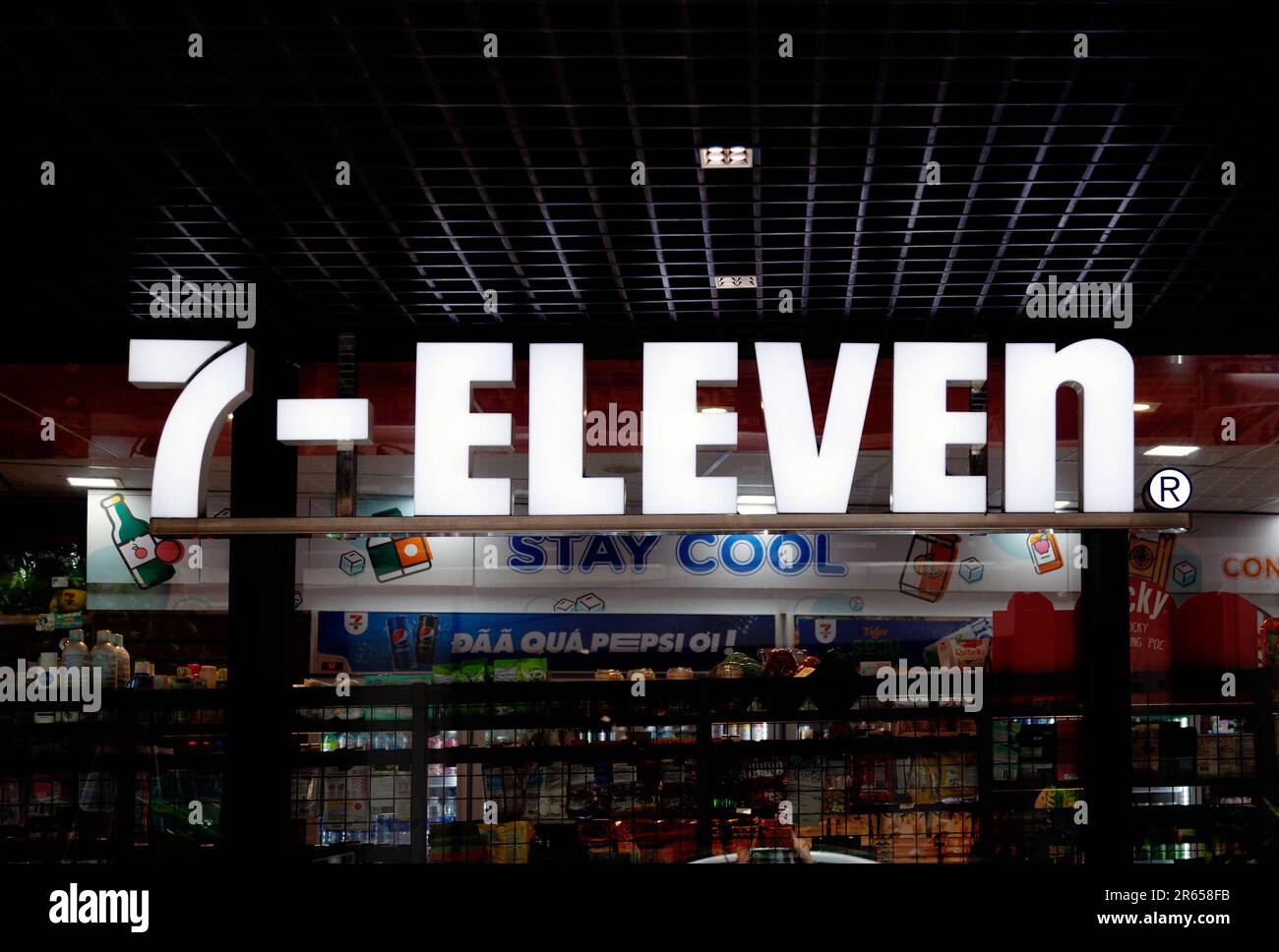 Ho-Chi-Minh-Stadt, Vietnam - 4. Juni 2023: Weißes Schild mit elektrischem Licht und 7-11-Logo auf einem 24-Stunden-Geschäft. Glänzende Werbung vor einem Supermarkt Stockfoto