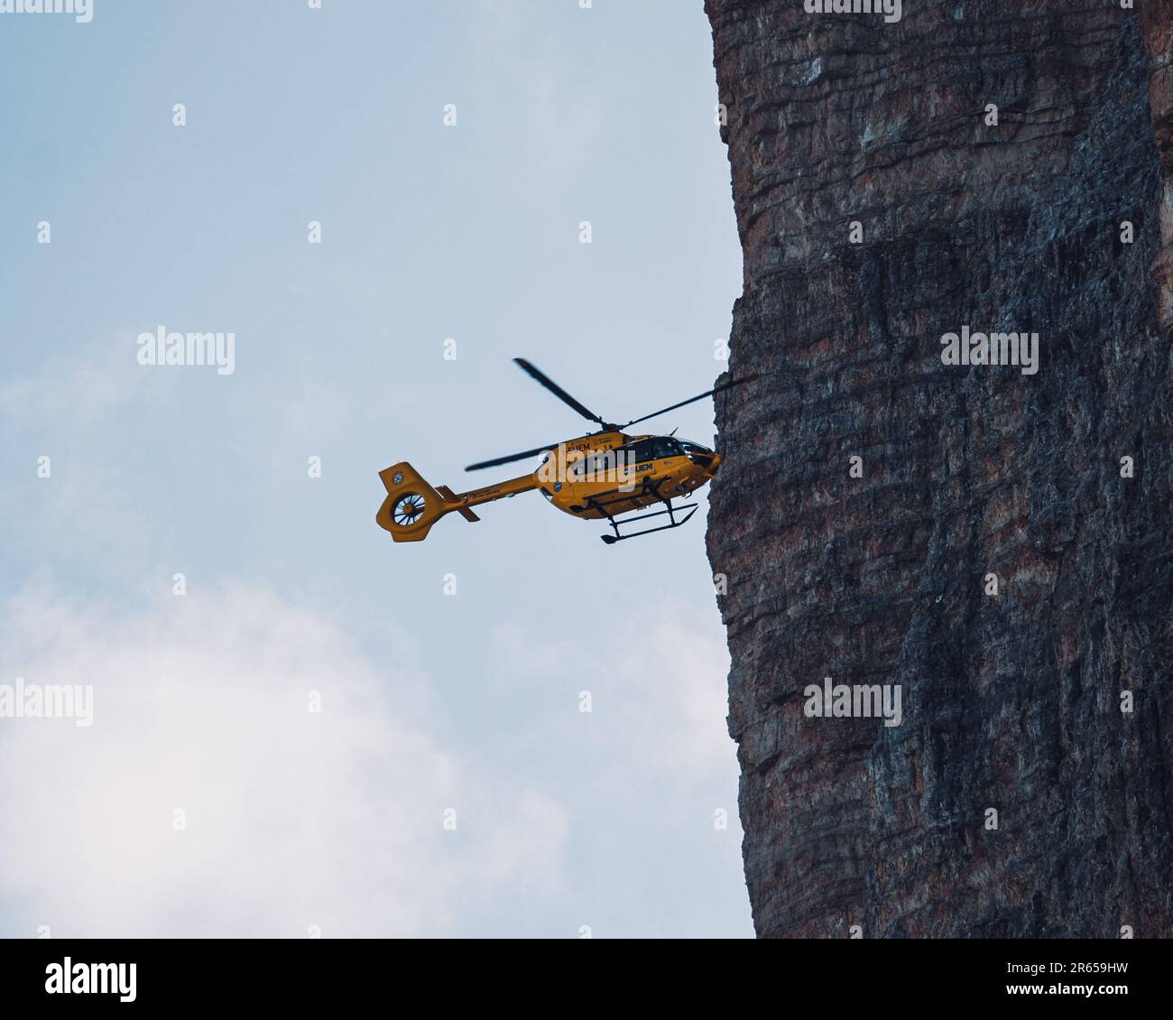 Ein Hubschrauber, der über einer felsigen Klippe fliegt, bietet eine weitläufige Perspektive auf die Landschaft in Italien, Trentino Stockfoto