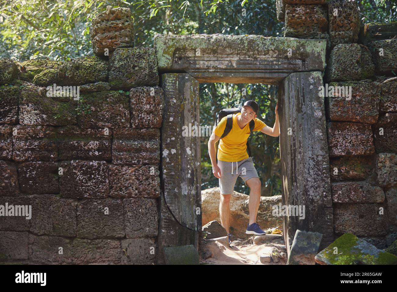 Ein Mann, der durch alte Ruinen geht und zu einem geheimnisvollen antiken Tempel mitten im Dschungel kommt. Reisender in Kambodscha. Stockfoto