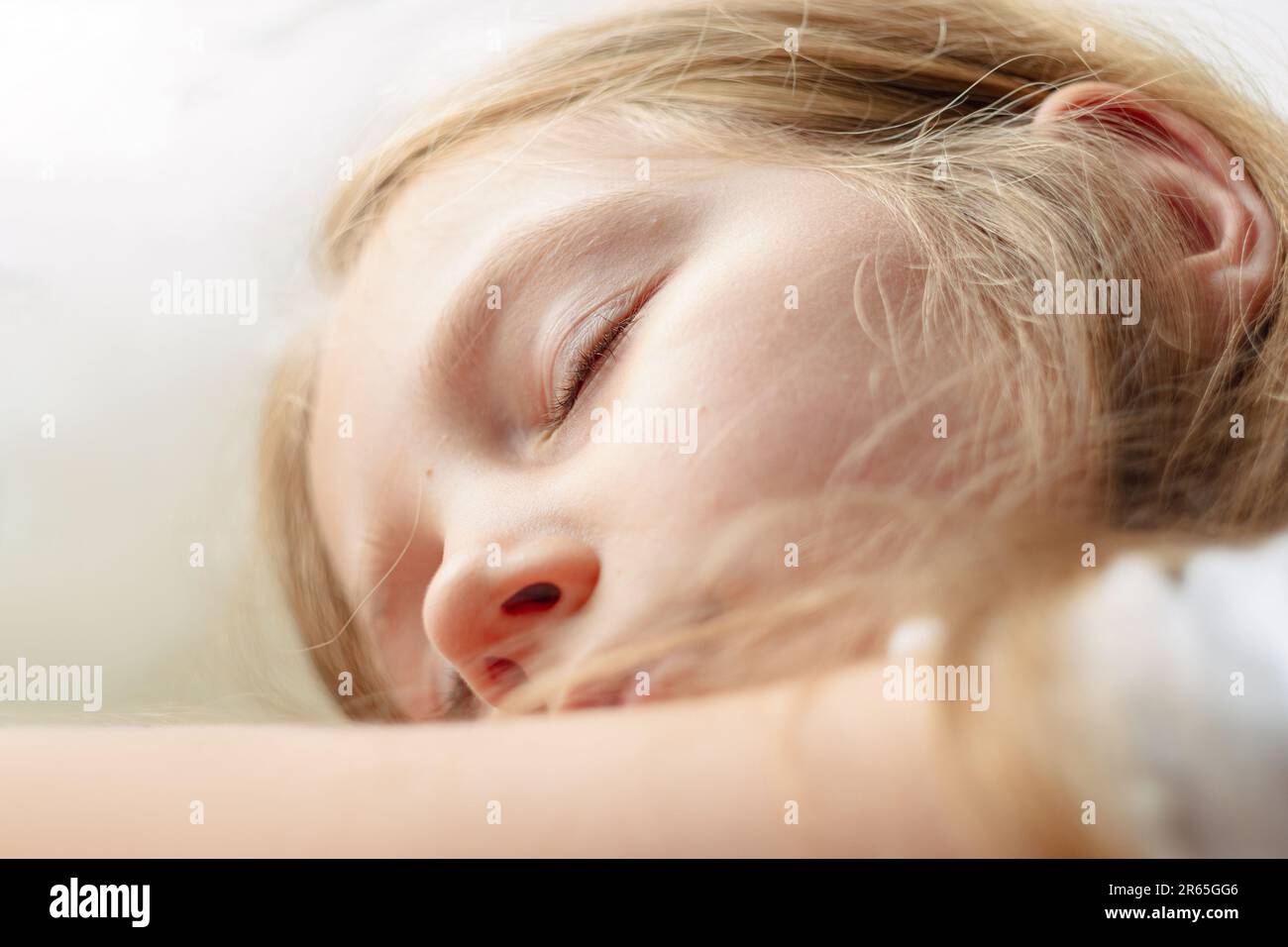 Ein ruhiges blondes Mädchen schläft auf einem weißen, weichen Kissen in einem bequemen Bett. Ein Kind mit geschlossenen Augen, Porträt-Nahaufnahme. Sleeping App Deep Sleep-Tracking so Stockfoto