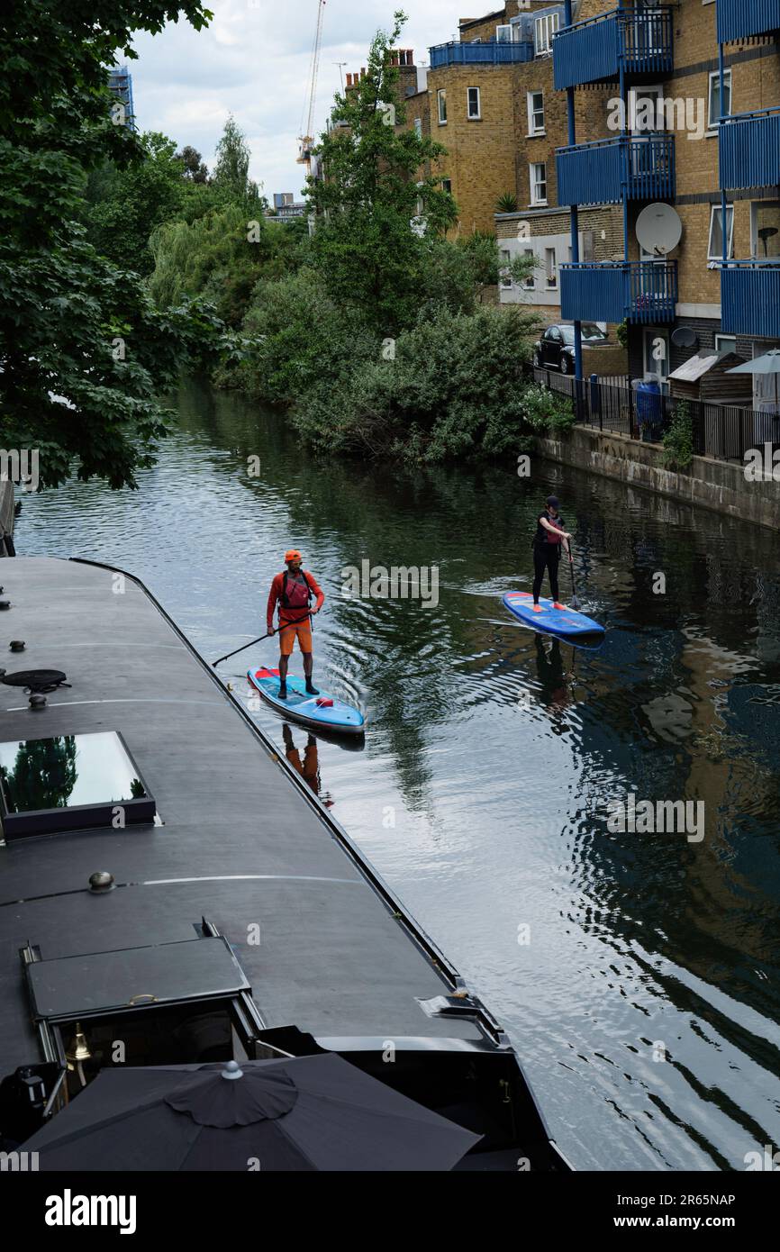 London - 05 21 2022 Uhr: Paddelboarder entlang des Grand Union Canal mit Hausbooten Stockfoto