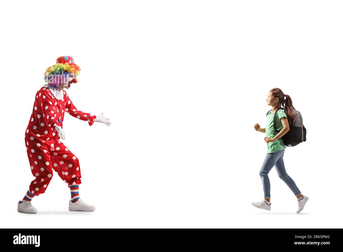 Ein Mädchen mit einem Rucksack läuft auf einen Clown zu, isoliert auf weißem Hintergrund Stockfoto