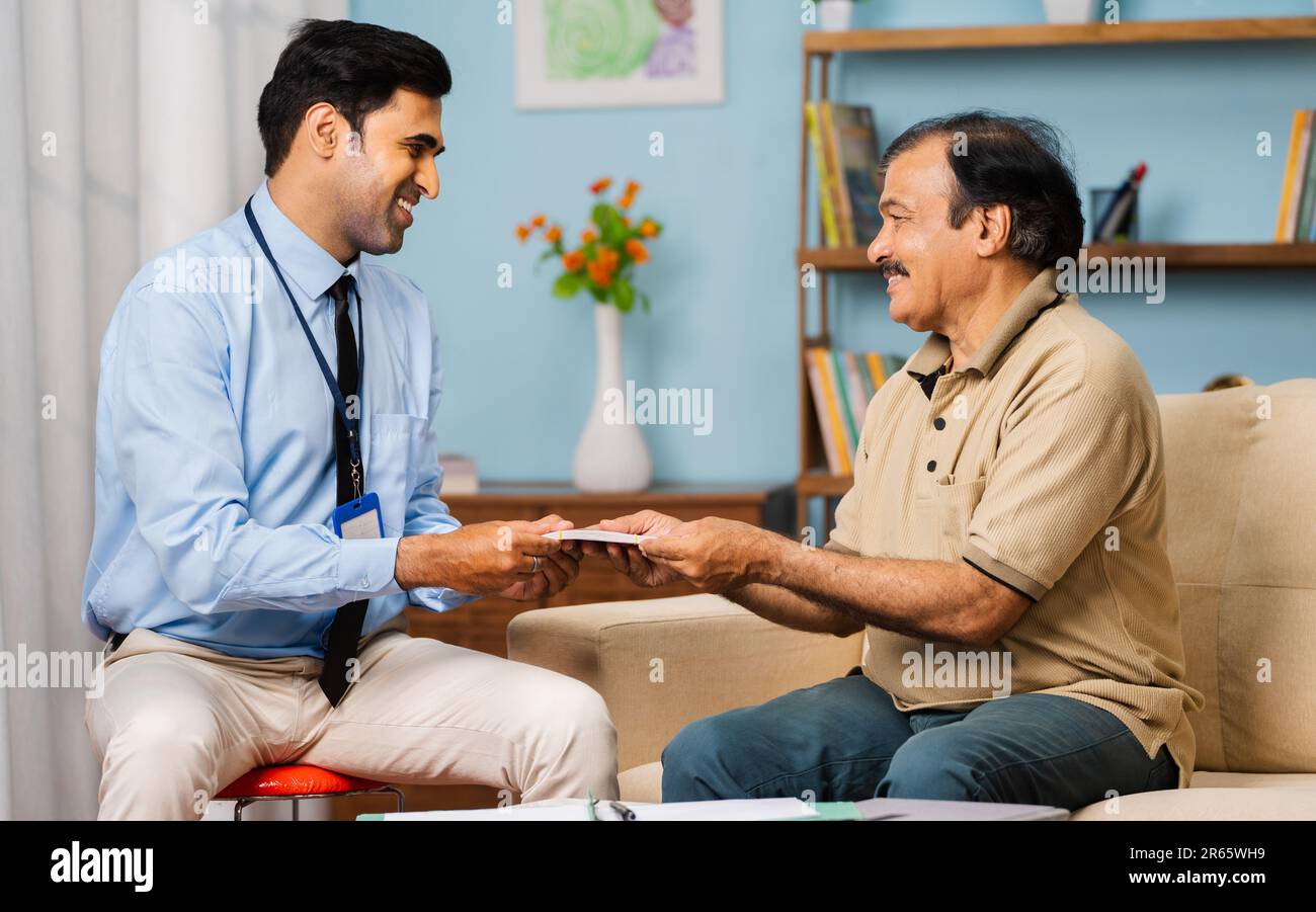 Glücklicher indischer Bankier, der zu Hause Versicherungspolice zahlt - Konzept der Kreditgenehmigung, finanziellen Unterstützung und Lebensweise im Ruhestand Stockfoto