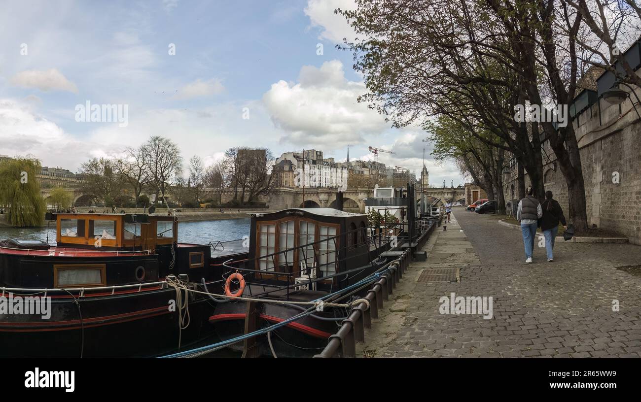 Panoramablick auf angedockte Boote und Menschen, die am Ufer der seine spazieren. Paris, Frankreich. 26. März 2023. Stockfoto