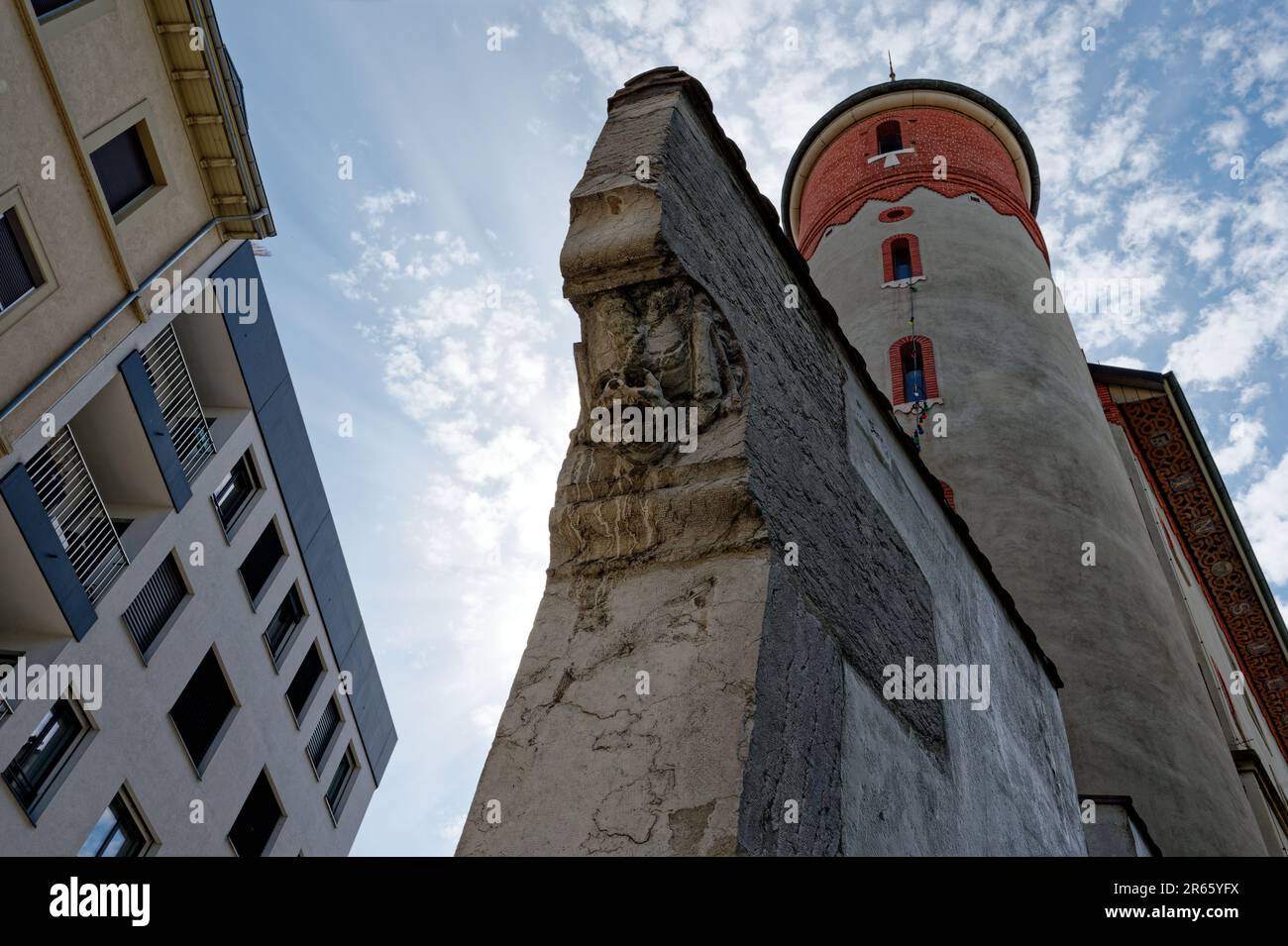Eine architektonische Nahaufnahme einer Reliefskulptur, die einem Schädel ähnelt, auf einer alten Ecksäule im Plainpalais, Genf, unter einem wolkenblauen Himmel. Stockfoto