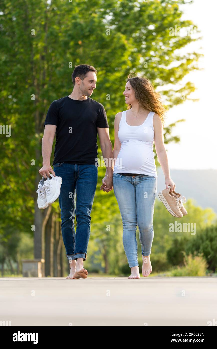Schwangere Frau mit ihrem Partner, die barfuß durch den Park geht Stockfoto