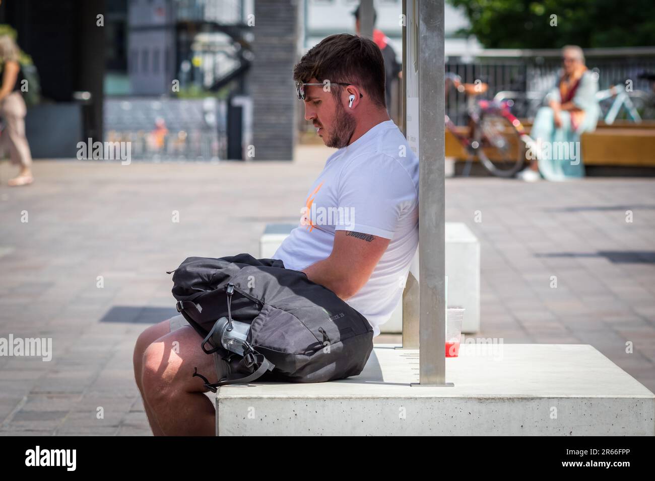 London, Großbritannien - 21. Juni 2023 - Hitzewelle in London, ein Mann bleibt im Schatten, um am Granary Square in Kings Cross kühl zu bleiben Stockfoto