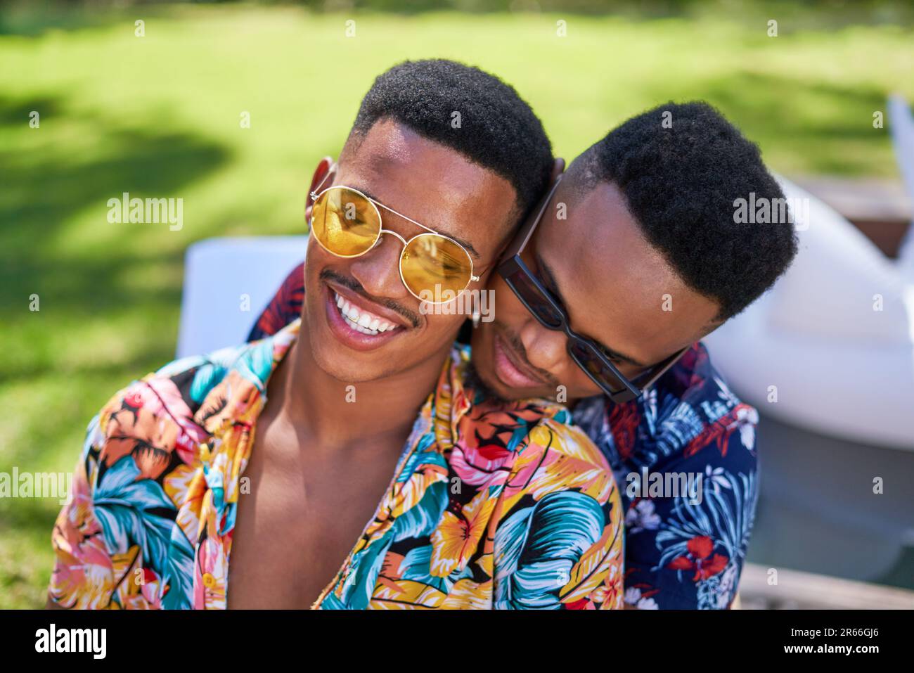 Glückliches junges schwules Paar mit Sonnenbrille, das sich umarmt Stockfoto