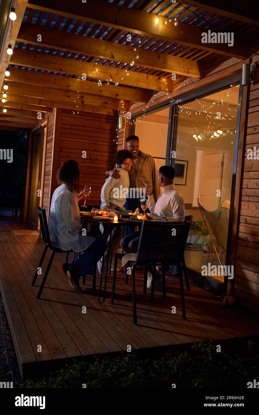 Glückliche Paare, die sich umarmten und das Abendessen auf der Terrasse genießen Stockfoto