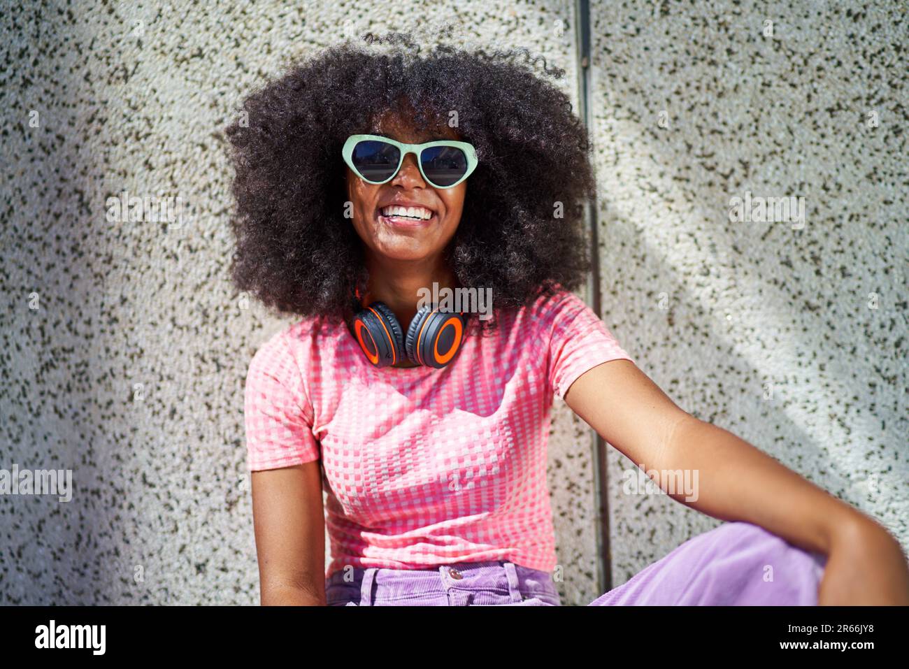 Porträt glückliche junge Frau in Sonnenbrille mit Kopfhörern Stockfoto
