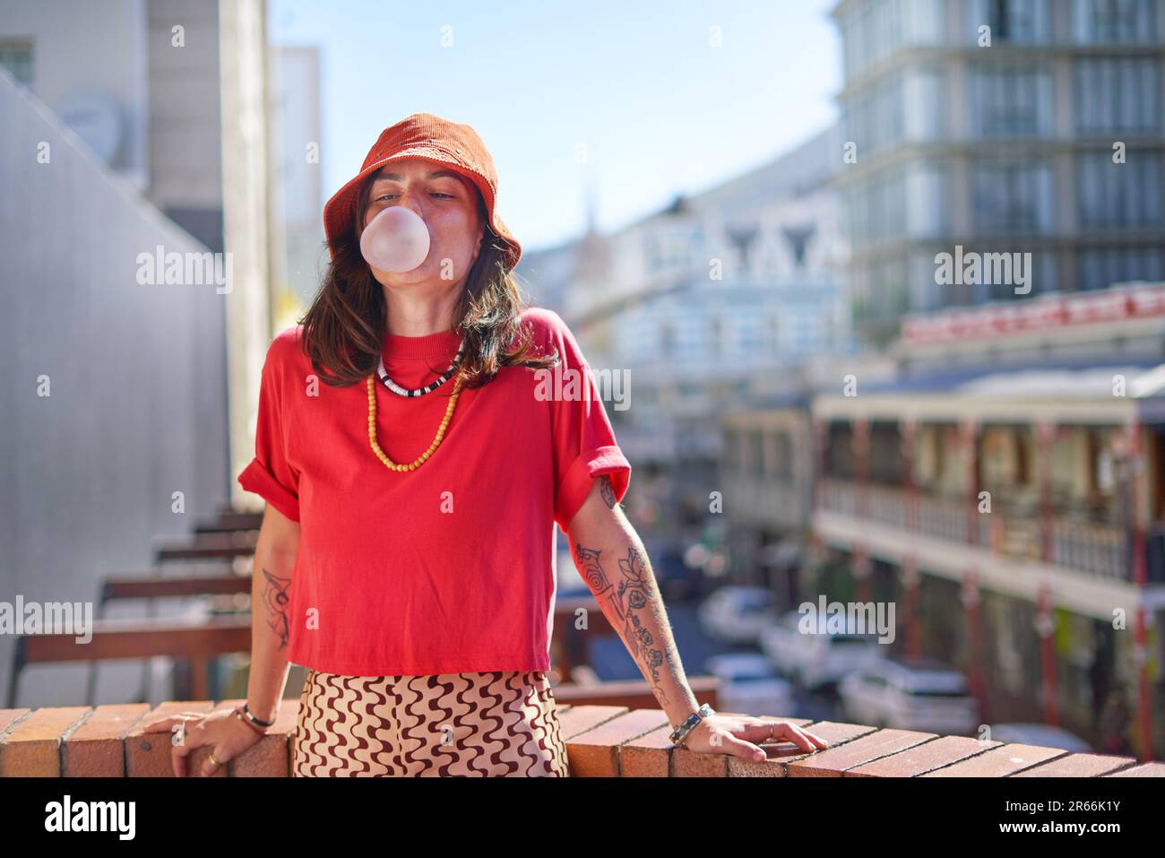 Porträt einer jungen Frau, die Kaugummiblase auf dem Dach bläst Stockfoto
