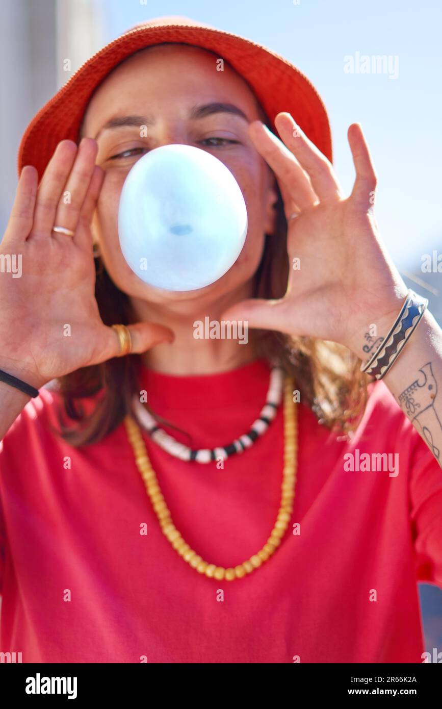 Nahaufnahme des Porträts einer jungen Frau, die mit Kaugummi Luftblasen bläst Stockfoto