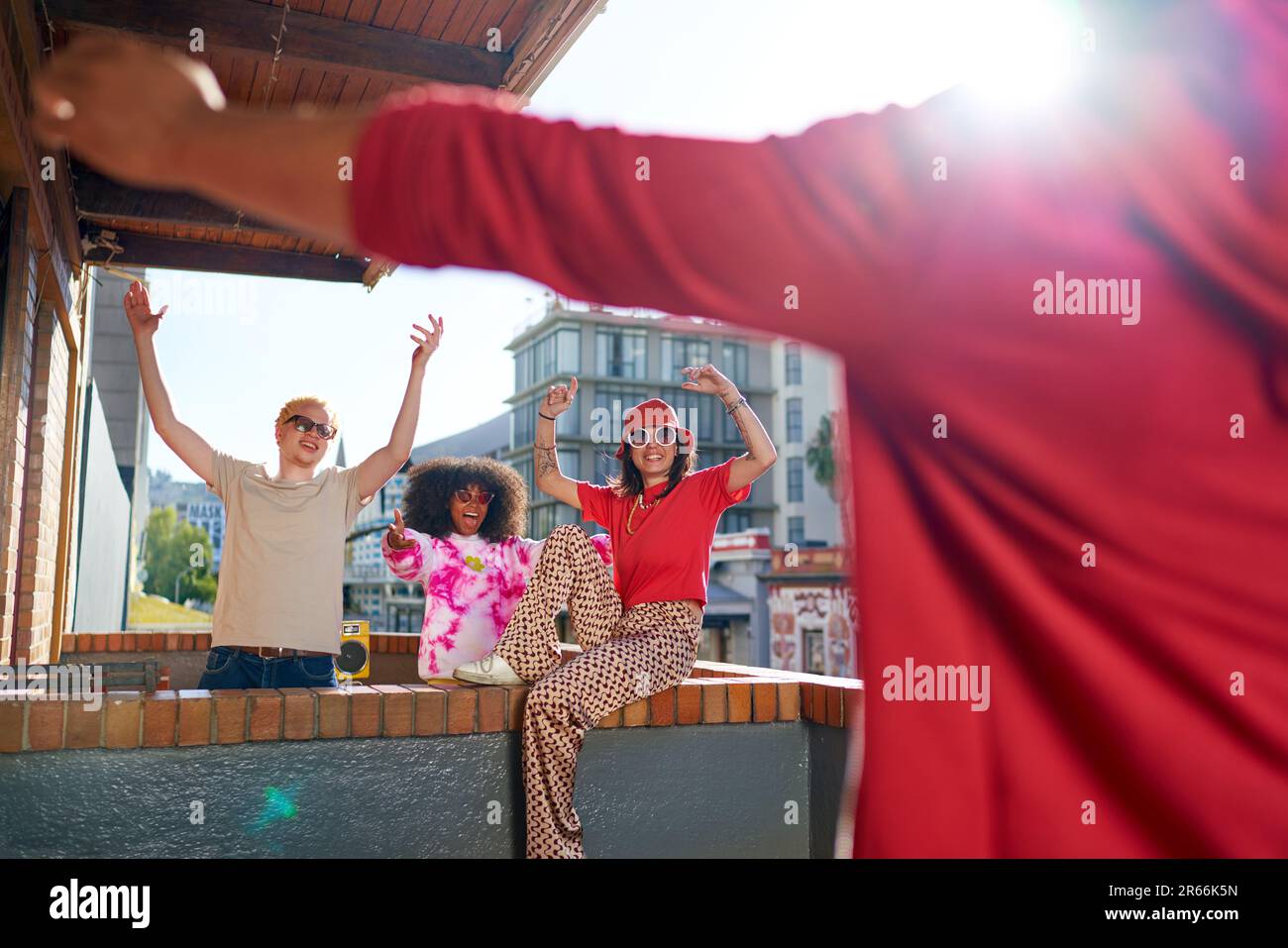 Fröhliche junge Freunde jubeln auf dem sonnigen, urbanen Balkon des Apartments Stockfoto