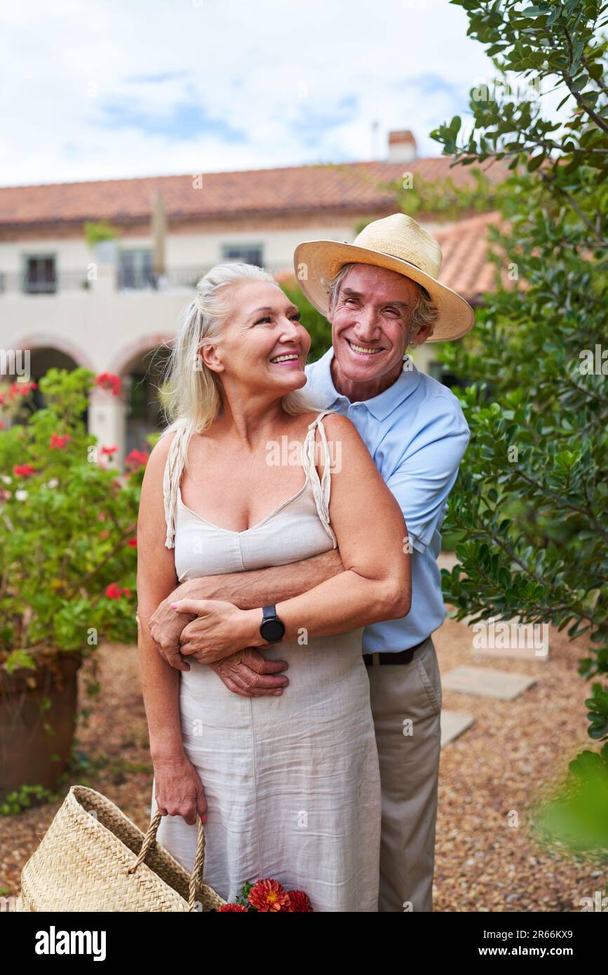 Portrait glückliches Seniorenpaar, das sich vor der Sommervilla umarmt Stockfoto