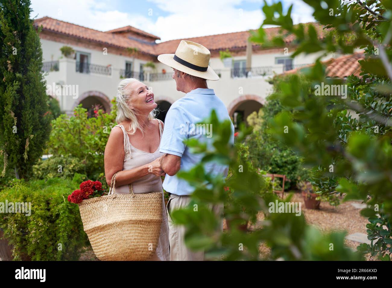 Glückliches, liebevolles Seniorenpaar, das sich im Villengarten unterhält Stockfoto