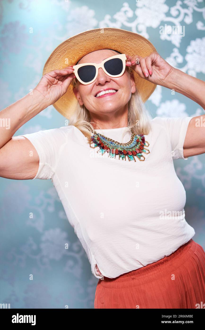 Portrait sorgenfreie Seniorin mit Sonnenbrille und Strohhut Stockfoto