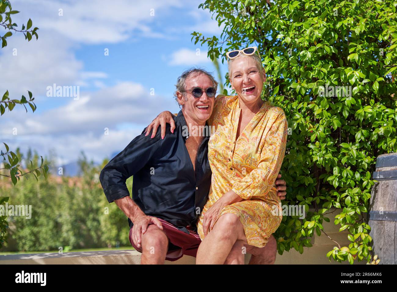 Portrait glückliches, sorgenfreies Seniorenpaar, das auf der sonnigen Sommerterrasse lacht Stockfoto