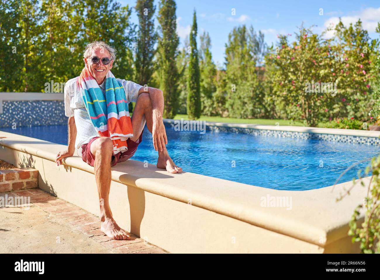 Porträt glücklicher Seniorenmann, der sich im sonnigen Swimmingpool entspannt Stockfoto