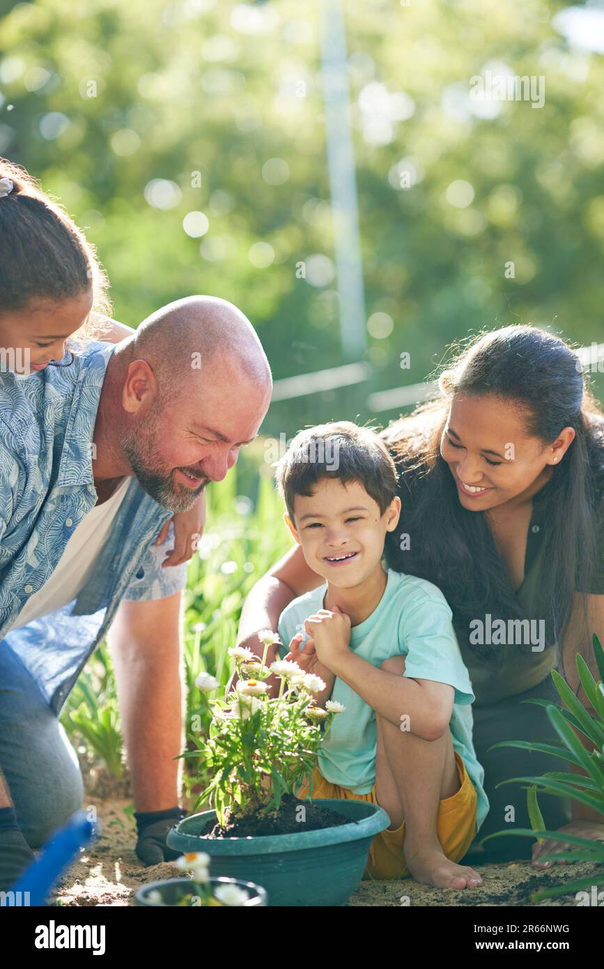 Glücklicher Junge mit Down-Syndrom, der Blumen mit der Familie im Garten pflanzt Stockfoto