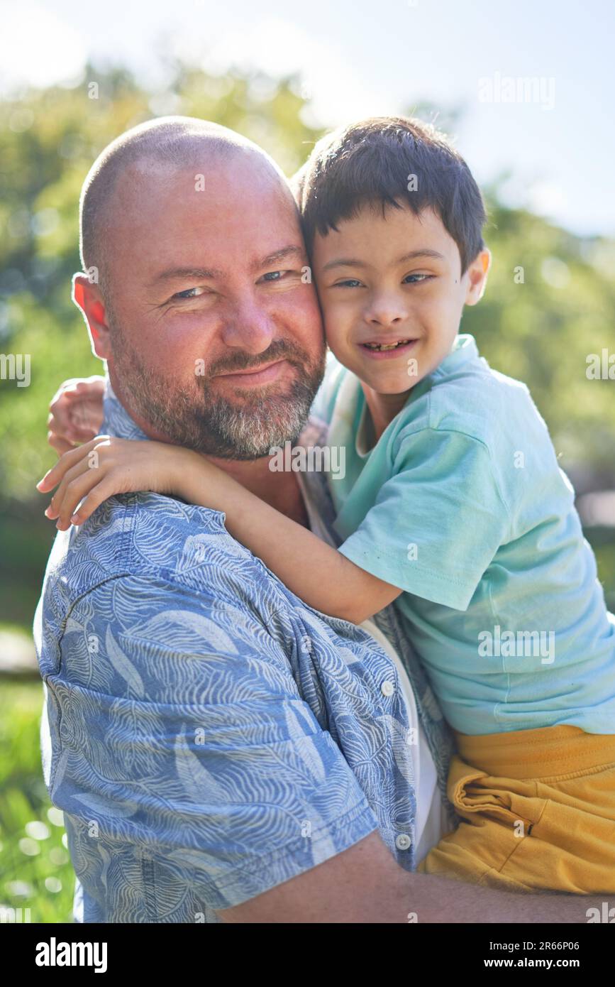 Porträt lächelnder Vater hält süßen Sohn mit Down-Syndrom Stockfoto