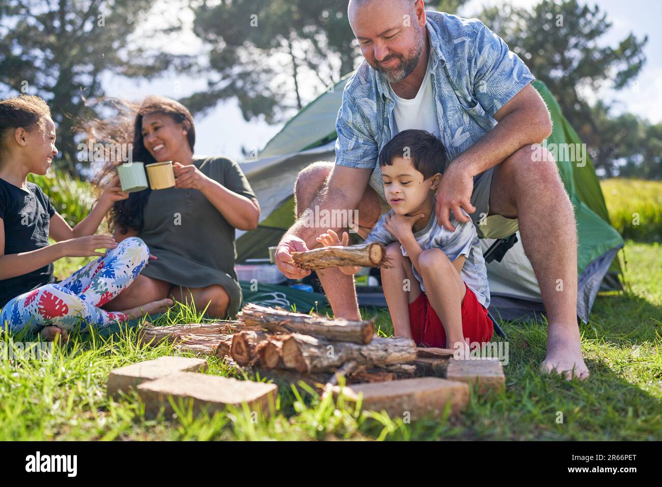 Vater und Sohn mit Down-Syndrom, die Feuerholz auf dem Campingplatz stapeln Stockfoto