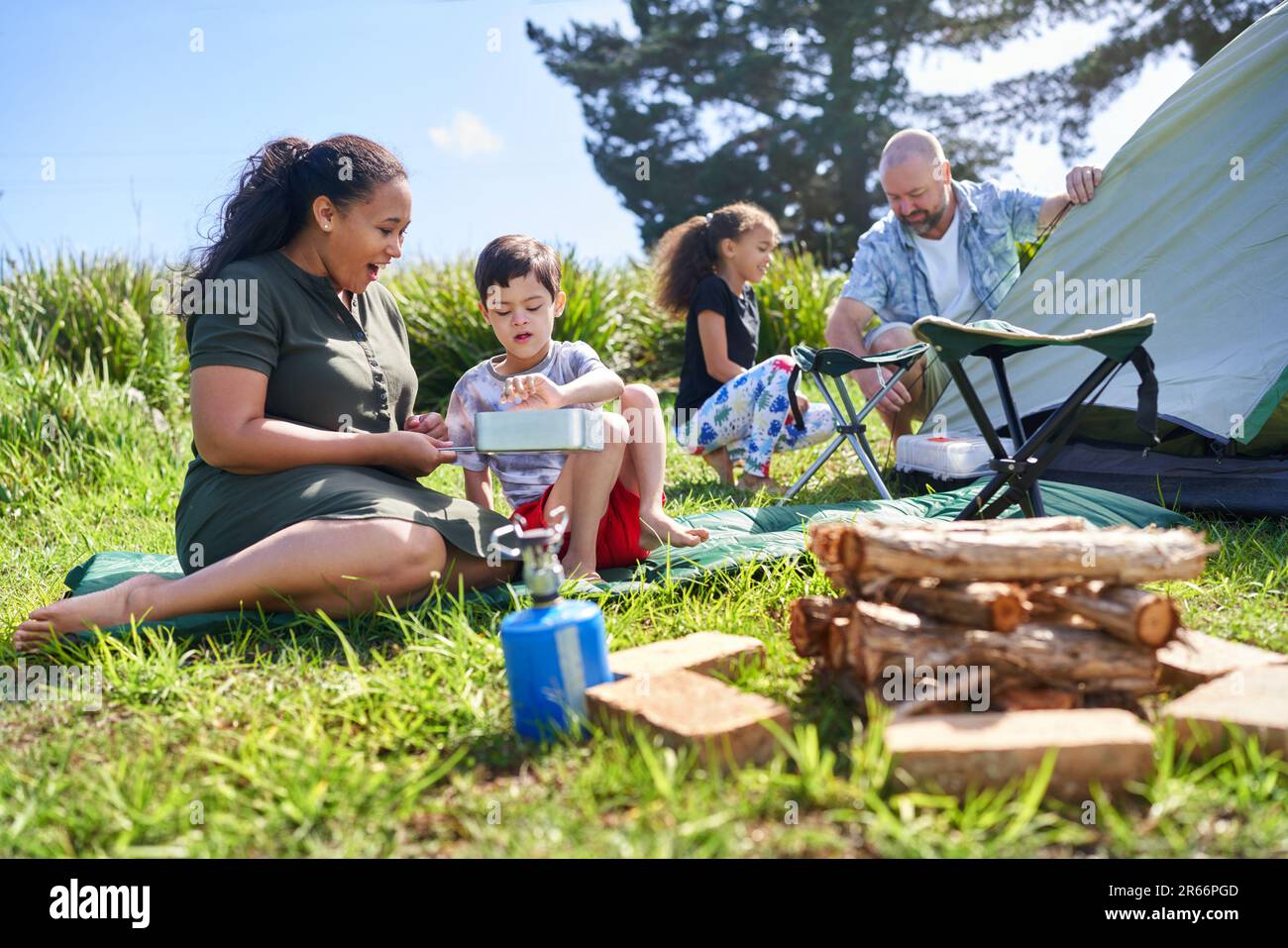 Familienkochen und Pitching-Zelt auf dem sonnigen Sommercampingplatz Stockfoto