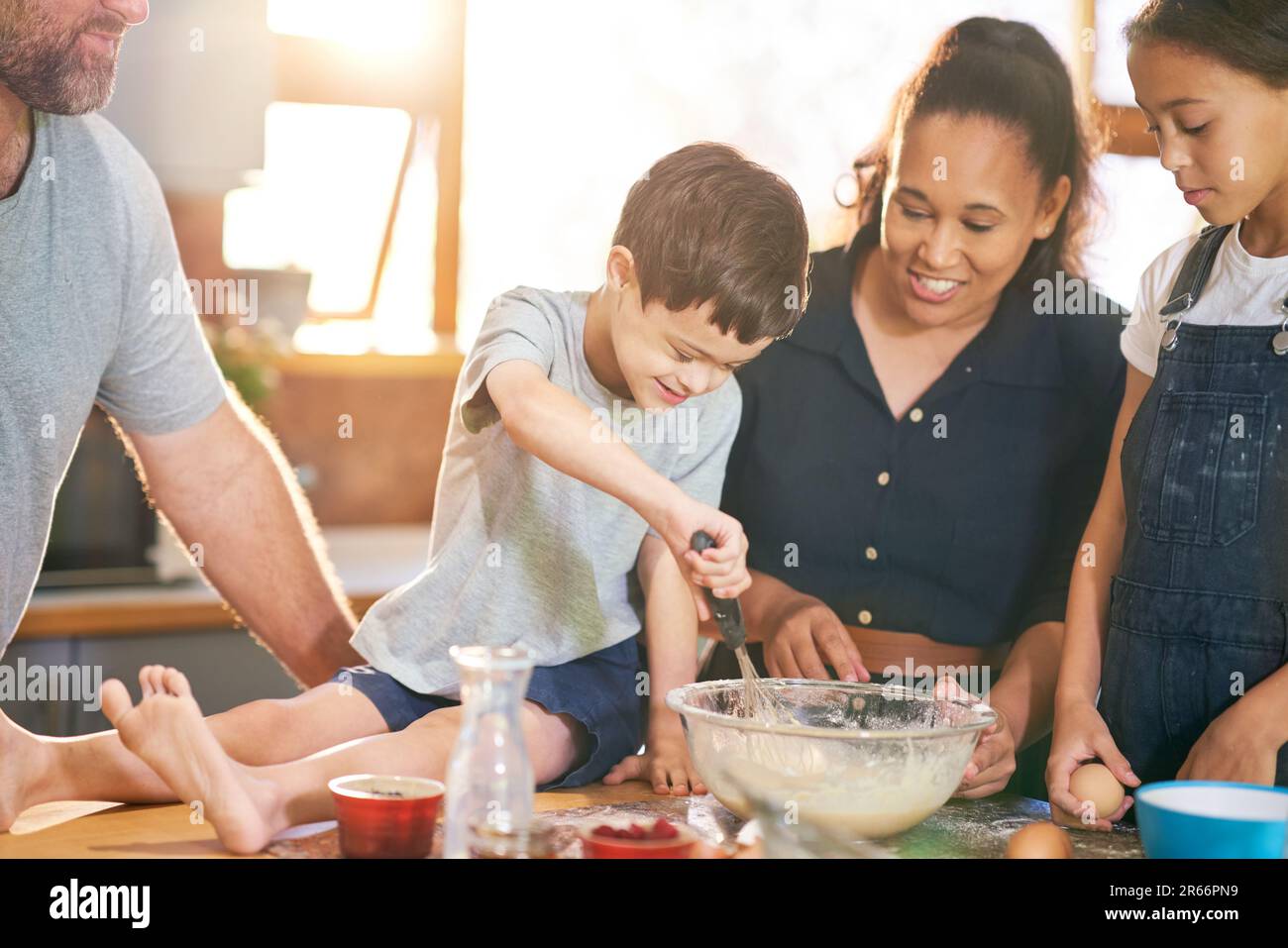 Glücklicher Junge mit Down-Syndrom, der mit der Familie in der Küche backt Stockfoto