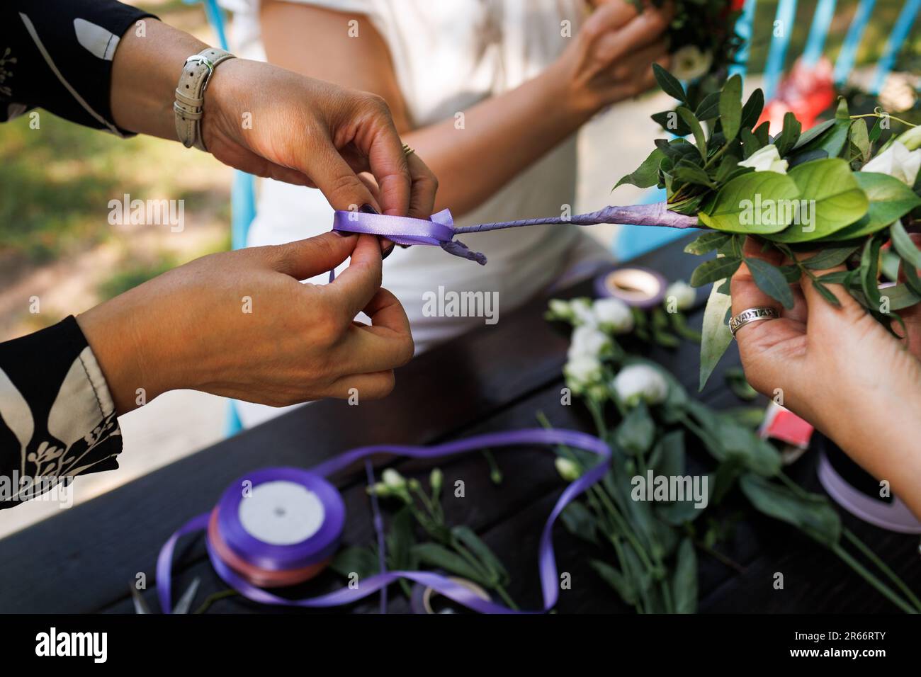 Wunderschöne junge Mädchen weben einen reichen Kranz aus Blumen, Eukalyptusästen, Früchten und Kräutern Stockfoto