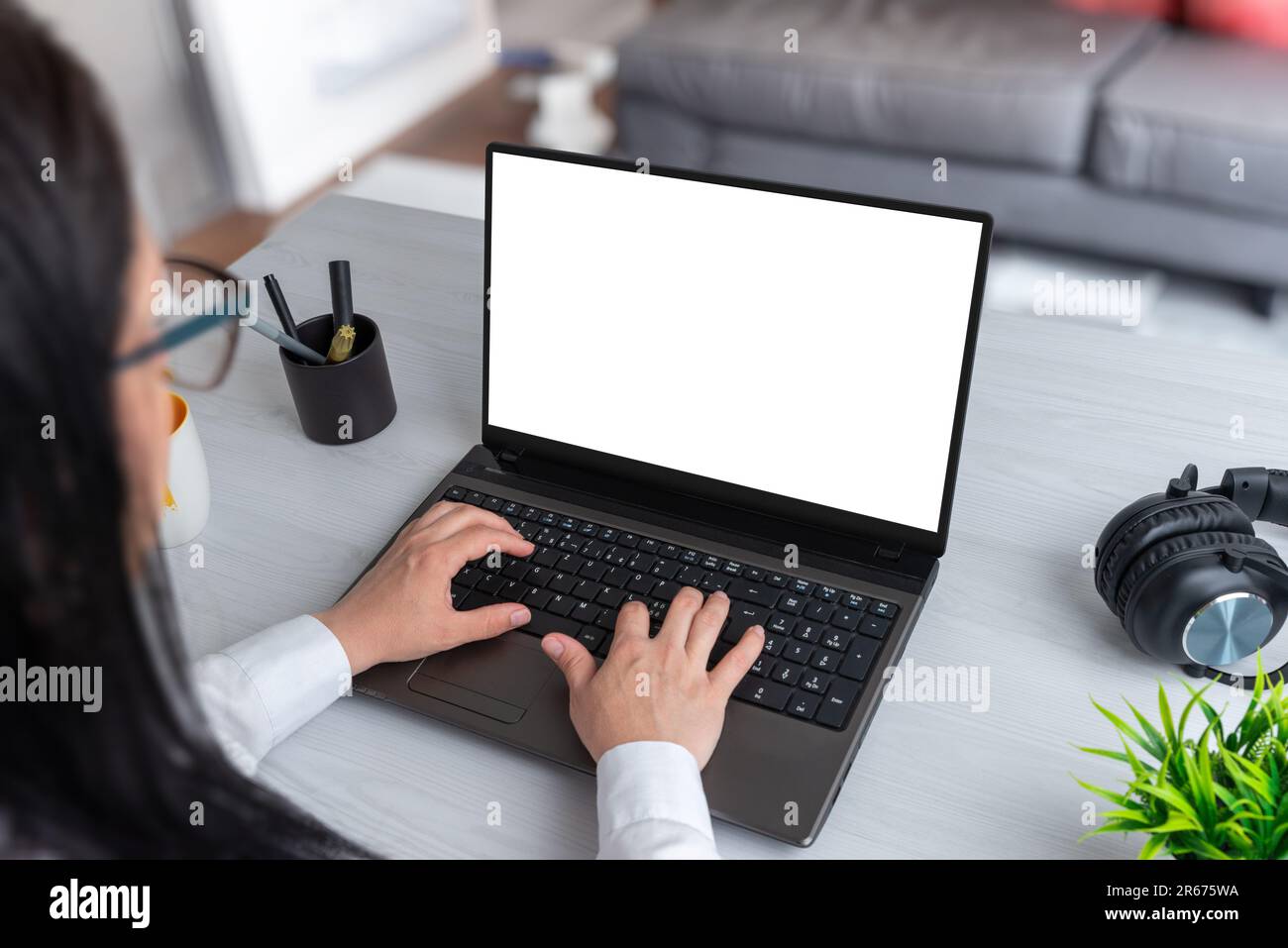 Frau arbeitet zu Hause auf einem Laptop mit isoliertem Bildschirm für die Webseitenpräsentation. Isolierter Bildschirm in Weiß. Wohnzimmer im Hintergrund Stockfoto
