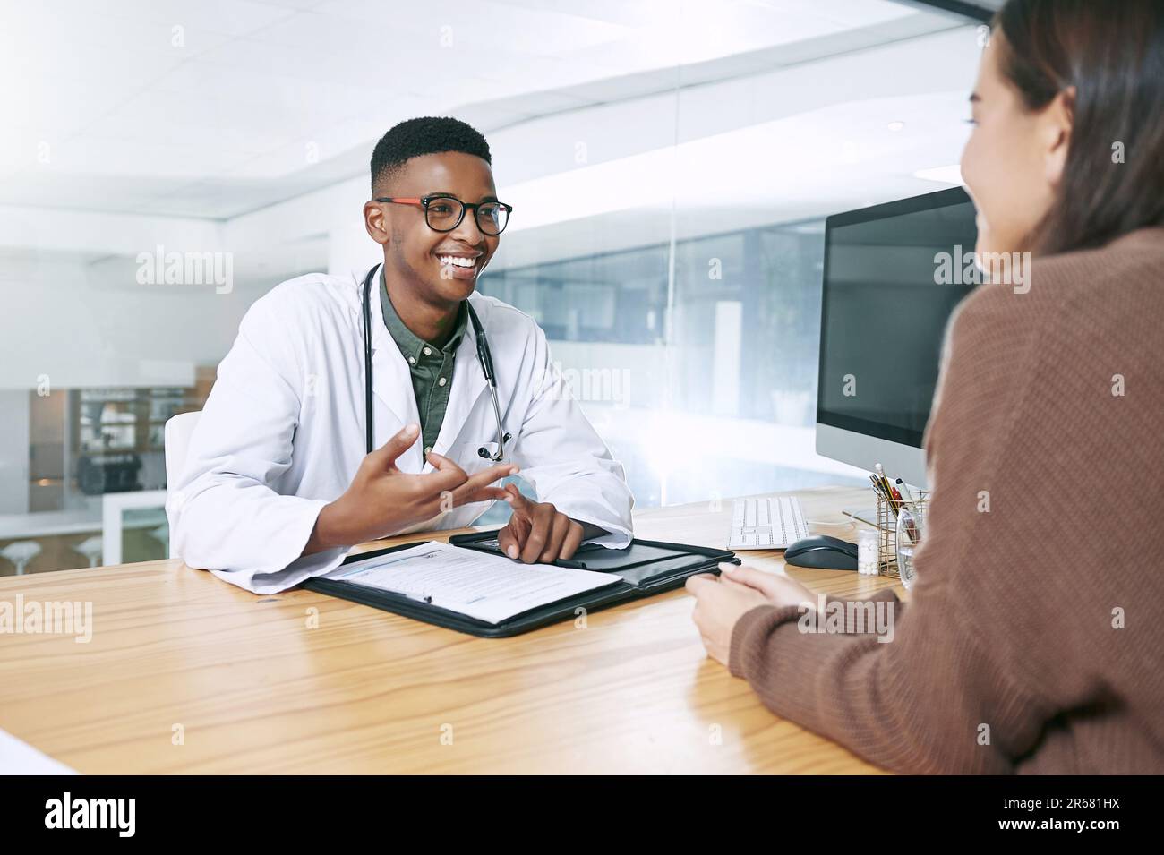 Bitte denken Sie an diese beiden Dinge. Ein gutaussehender Arzt, der bei seiner Patientin sitzt und ihre Diagnose während einer Sprechstunde in der Klinik erklärt. Stockfoto