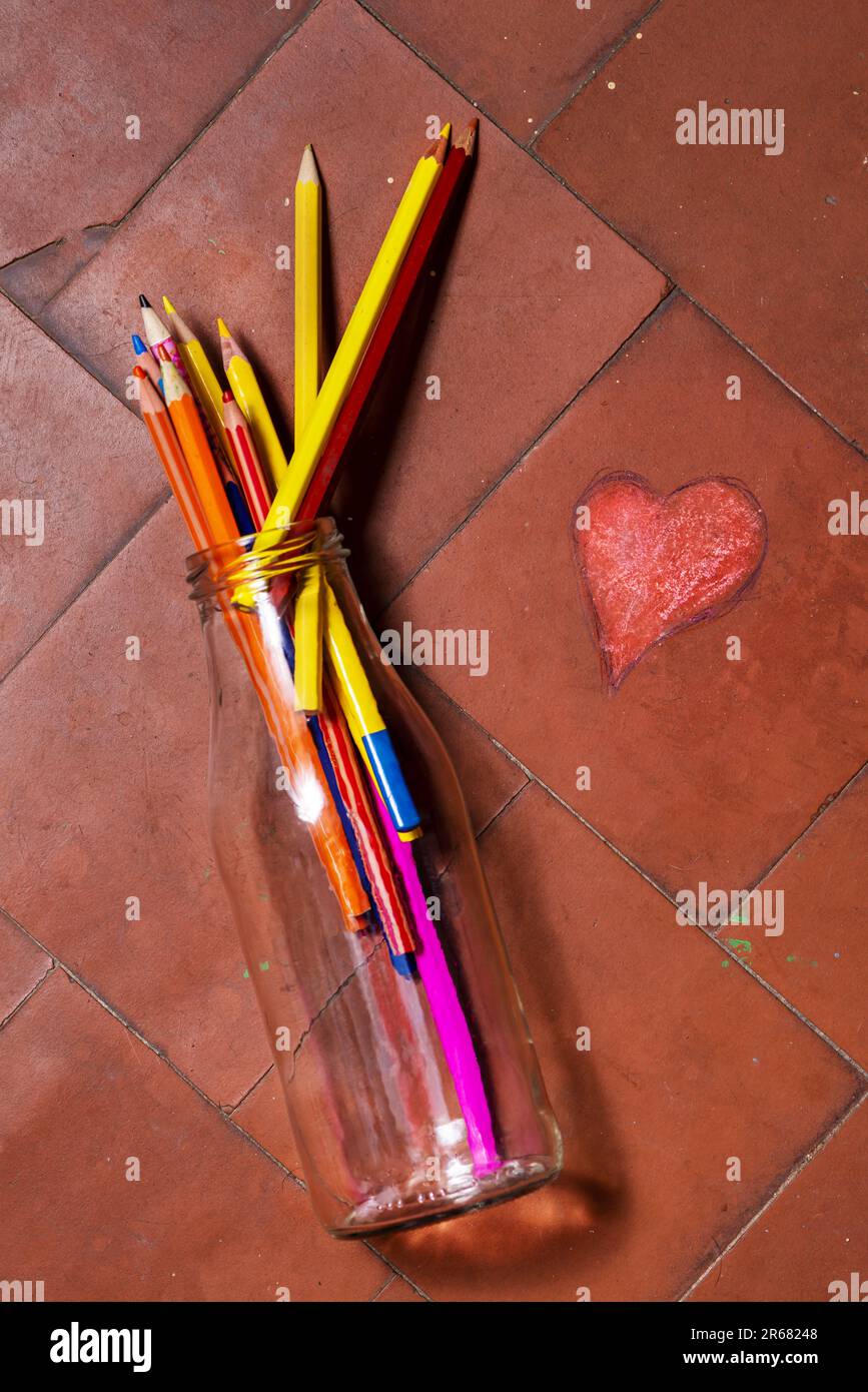 Stille Leben mit einer Glasflasche, die auf dem Boden voller bunter Bleistifte lag Stockfoto