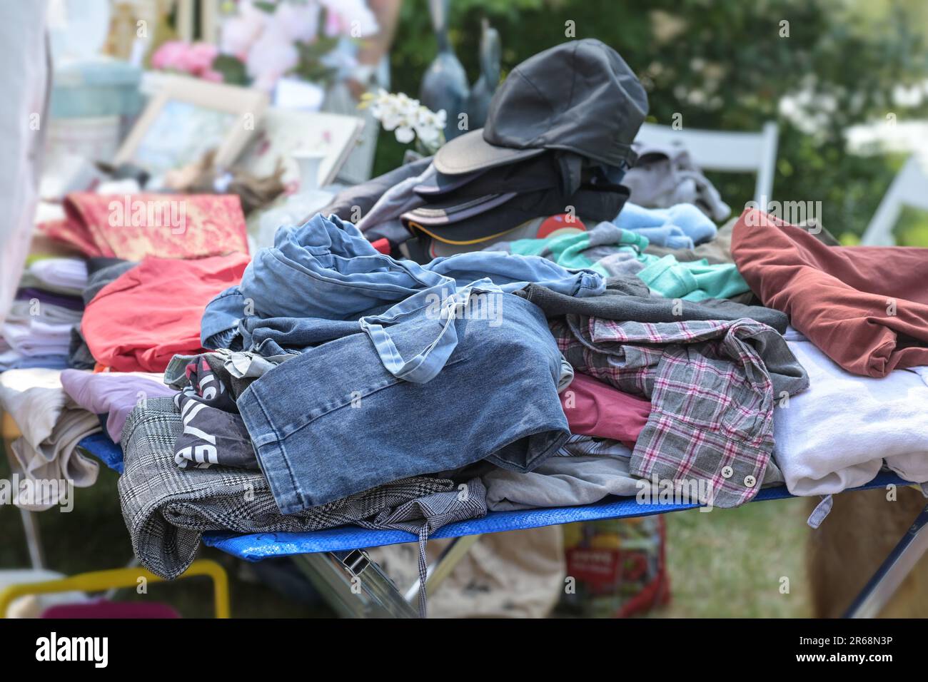 Gebrauchte Kleidung und Kappen zum Verkauf auf einem Flohmarkt oder Garagenmarkt an einem sonnigen Wochenendtag, Kopierbereich, ausgewählter Fokus Stockfoto