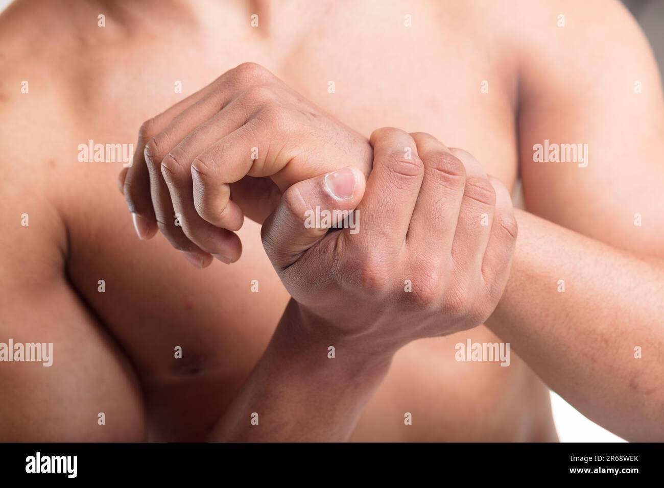 Männerhände im Fokus, eine greift das andere Handgelenk wegen Schmerzen, möglicherweise Tendinitis oder Karpaltunnelsyndrom Stockfoto