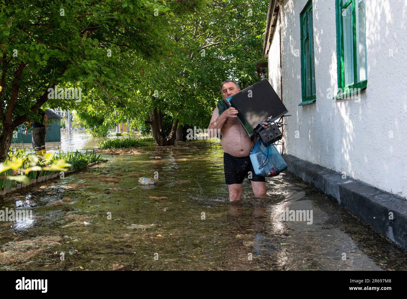 Ein Mann trägt einen Computermonitor und andere Elektronik von seinem Haus in einem überfluteten Viertel in Kherson, Ukraine, einen Tag nach dem Platzen des Kakhovka-Staudamms entlang des Dnipro-Flusses überflutete Gemeinden an beiden Ufern des Flusses südlich des Staudamms. In Dörfern entlang des Dnipro kam es infolge der Zerstörung des Kakhovka-Staudamms zu massiven Überschwemmungen, die die Gemeinden entlang des Flusses im Süden belasten und die Wasserstände für die Gemeinden im Norden gefährlich niedrig fielen. (Foto: Matthew Hatcher/SOPA Images/Sipa USA) Stockfoto