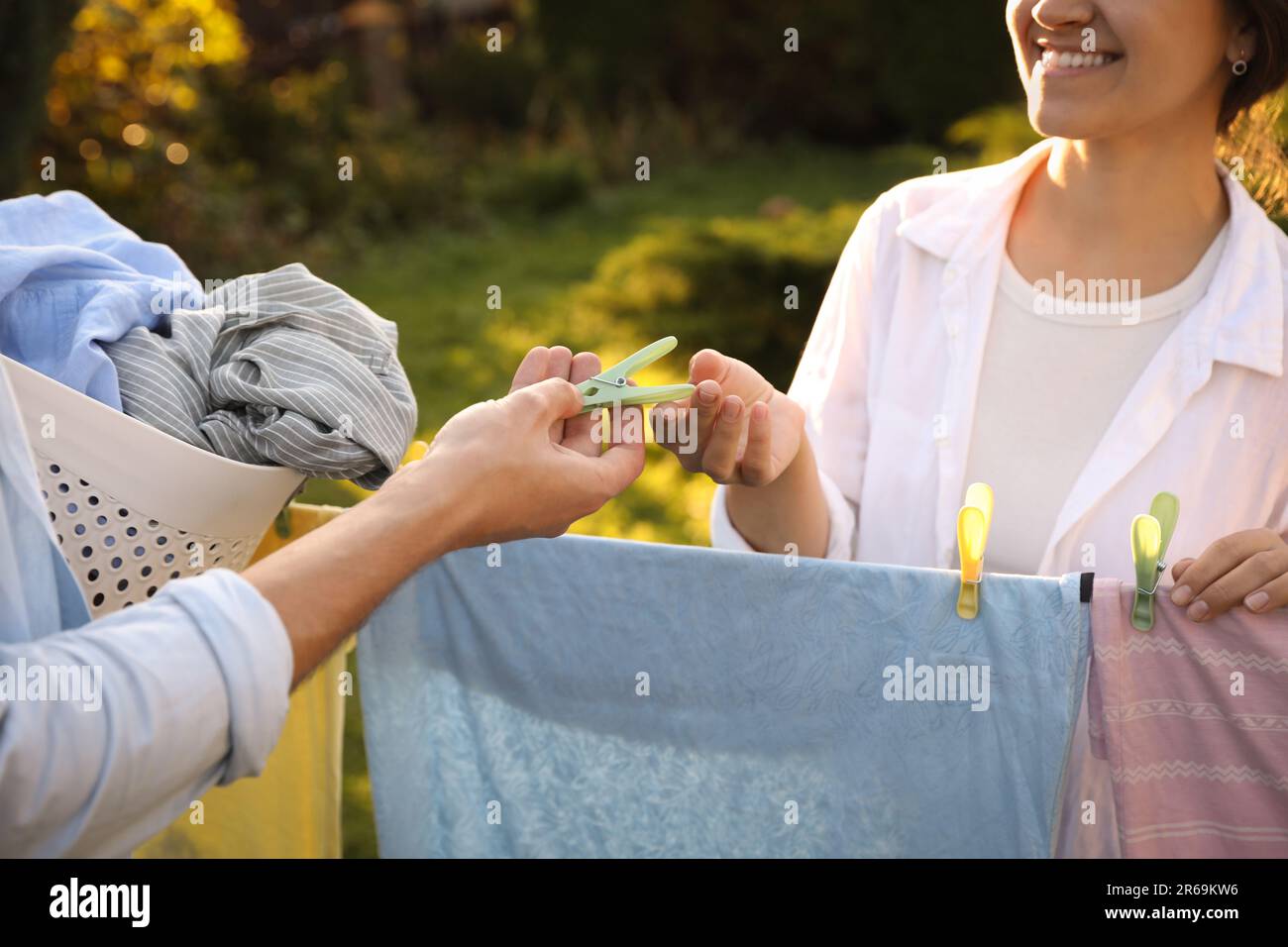 Glückliche Familie, die Kleidung aufhängt, mit Wäscheklammern an der Wäscheleine, zum Trocknen im Garten, Schließung Stockfoto