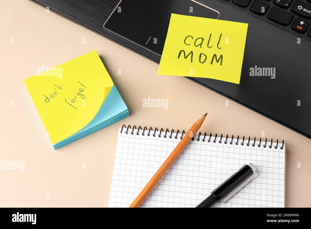 Notizen in Papierform mit Erinnerungen, Notizbuch und Laptop auf beigefarbenem Tisch, Ansicht oben Stockfoto