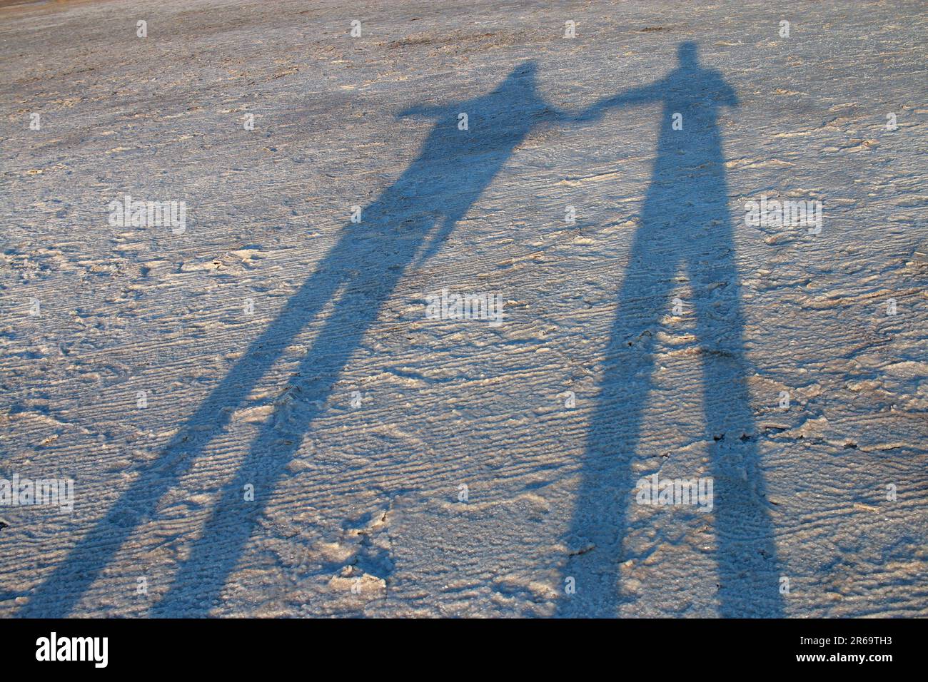 Das Foto wurde in der Ukraine in der Region Odessa aufgenommen. Das Bild zeigt den Schatten eines jungen Paares auf der Salzkruste der Flussmündung. Stockfoto