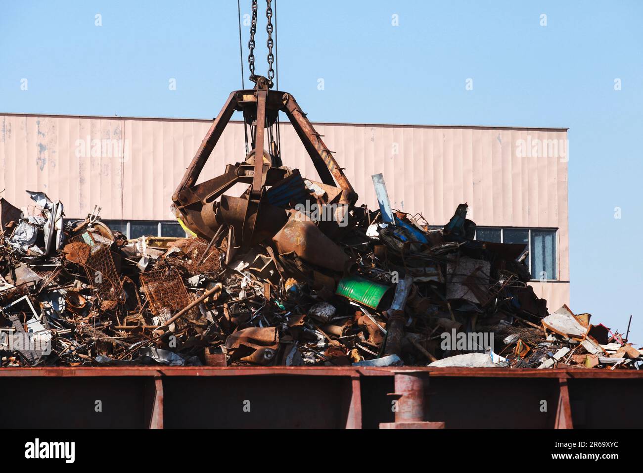 Der hydraulische Greifer nimmt rostigen Metallschrott zum Recycling an sonnigen Tagen auf Stockfoto