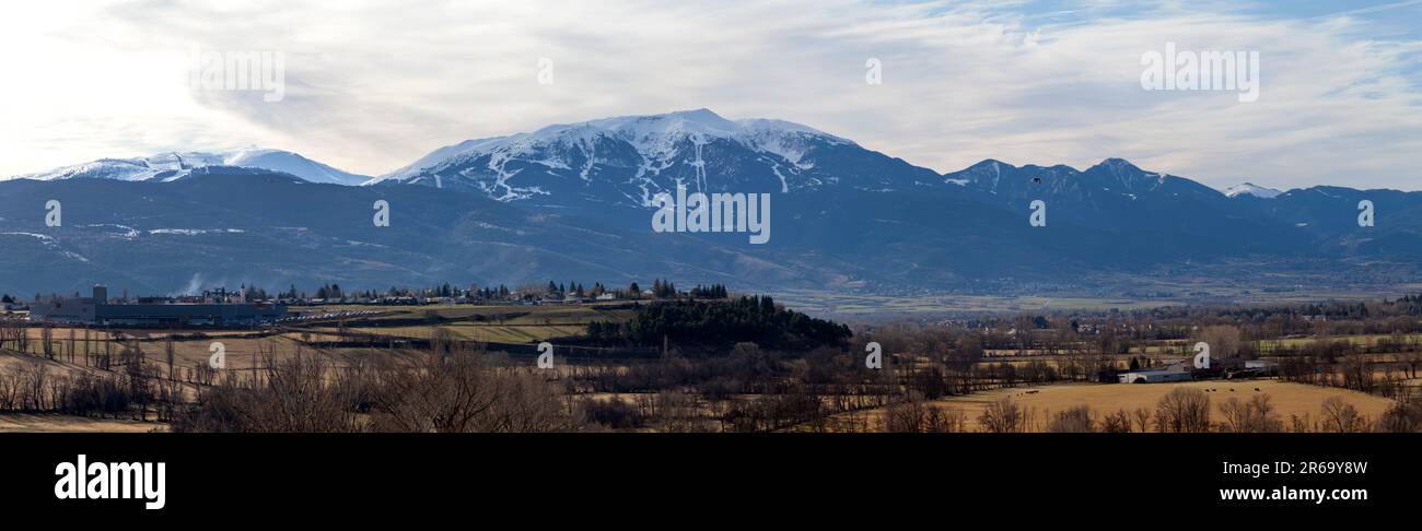 Panoramablick auf die schneebedeckten Berge in den Pyrenäen mit dem spanischen Dorf Puigcerdà im Vordergrund. Stockfoto
